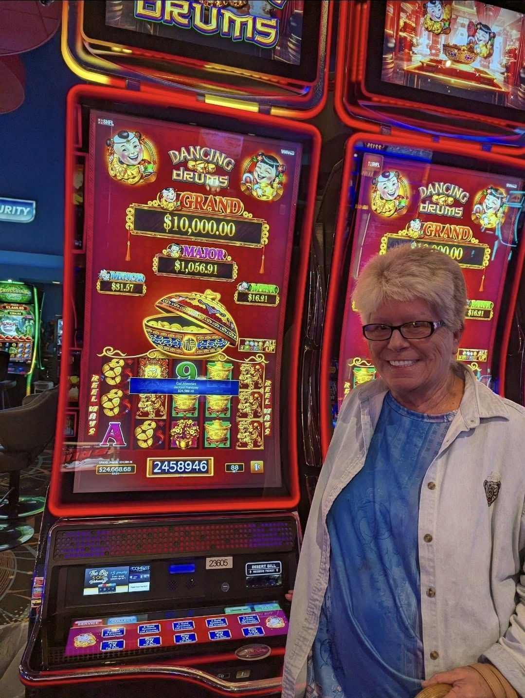 Smiling woman standing next to a Dancing Drums slot machine
